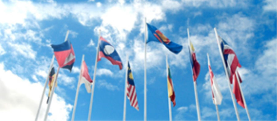 Many national flags waving against a blue sky with clouds.